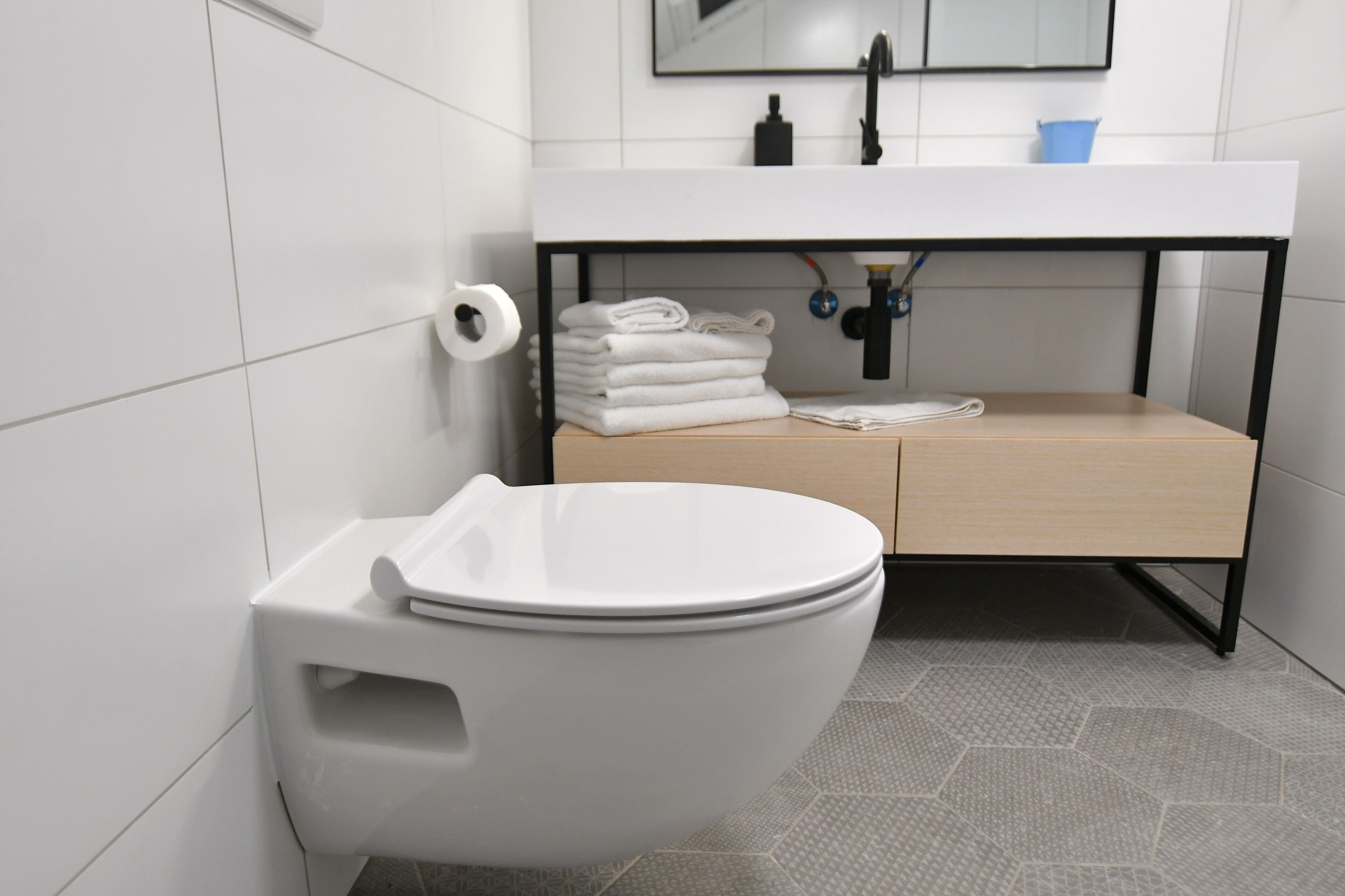 A modern bathroom with a white toilet, a sink with a wooden vanity, and a mirror above the sink.
