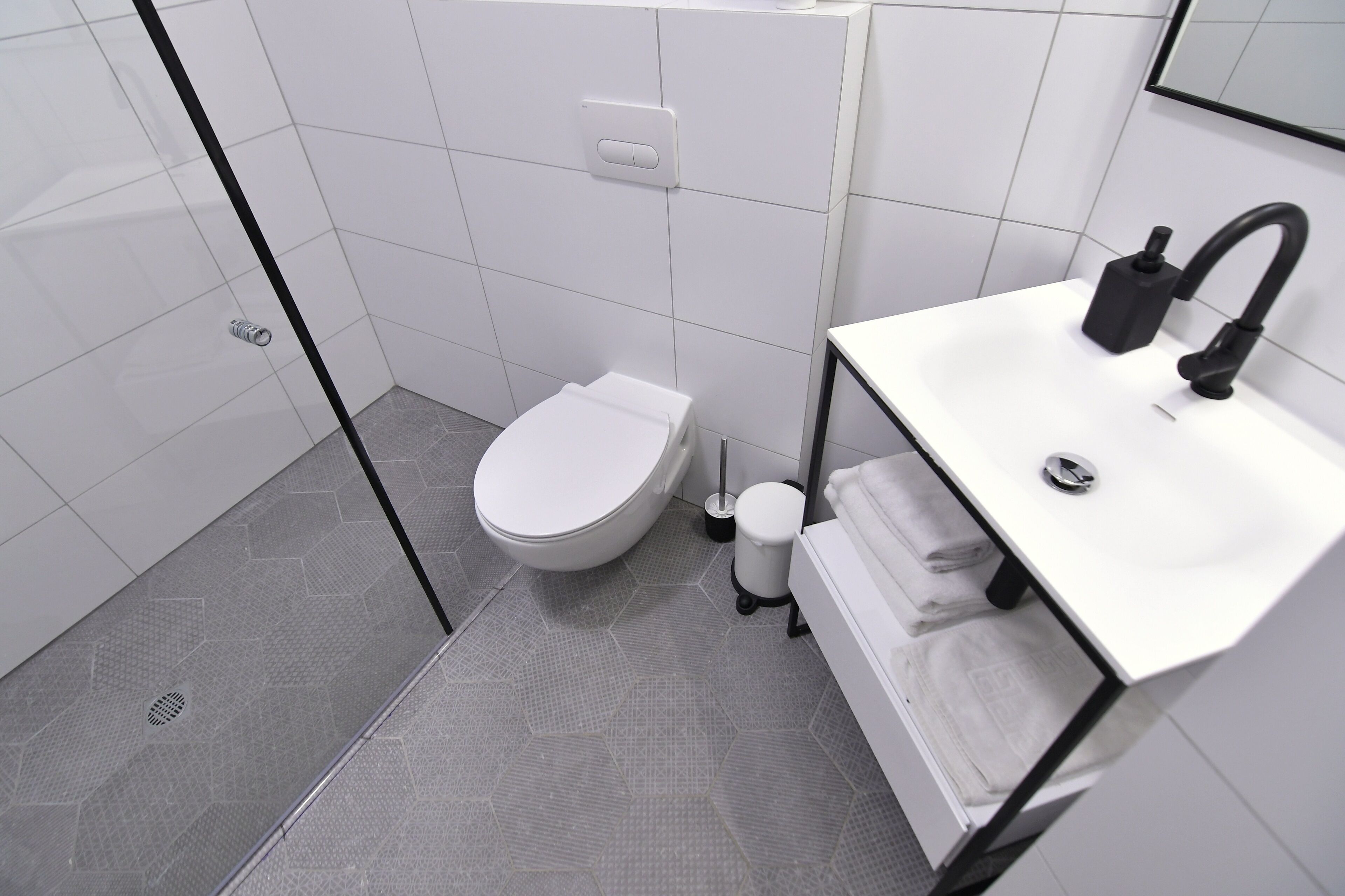 Une salle de bain moderne équipée de toilettes, d’un lavabo et d’une zone douche.