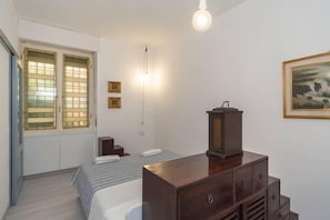 Ein Schlafzimmer mit einem Bett, einem Schminktisch und einem Fenster mit Jalousien.