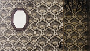Una stanza con carta da parati decorata, una panca in legno e uno specchio a parete.