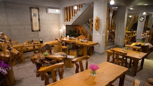 En restaurant med træmøbler, en trappe og et ur på væggen.