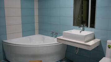 Un baño con una bañera grande, un lavabo y un inodoro.