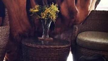 Ein Zimmer mit einer großen Holzskulptur, einem kleinen Tisch mit Blumenvase und einer schwarzen Tasche auf dem Boden.