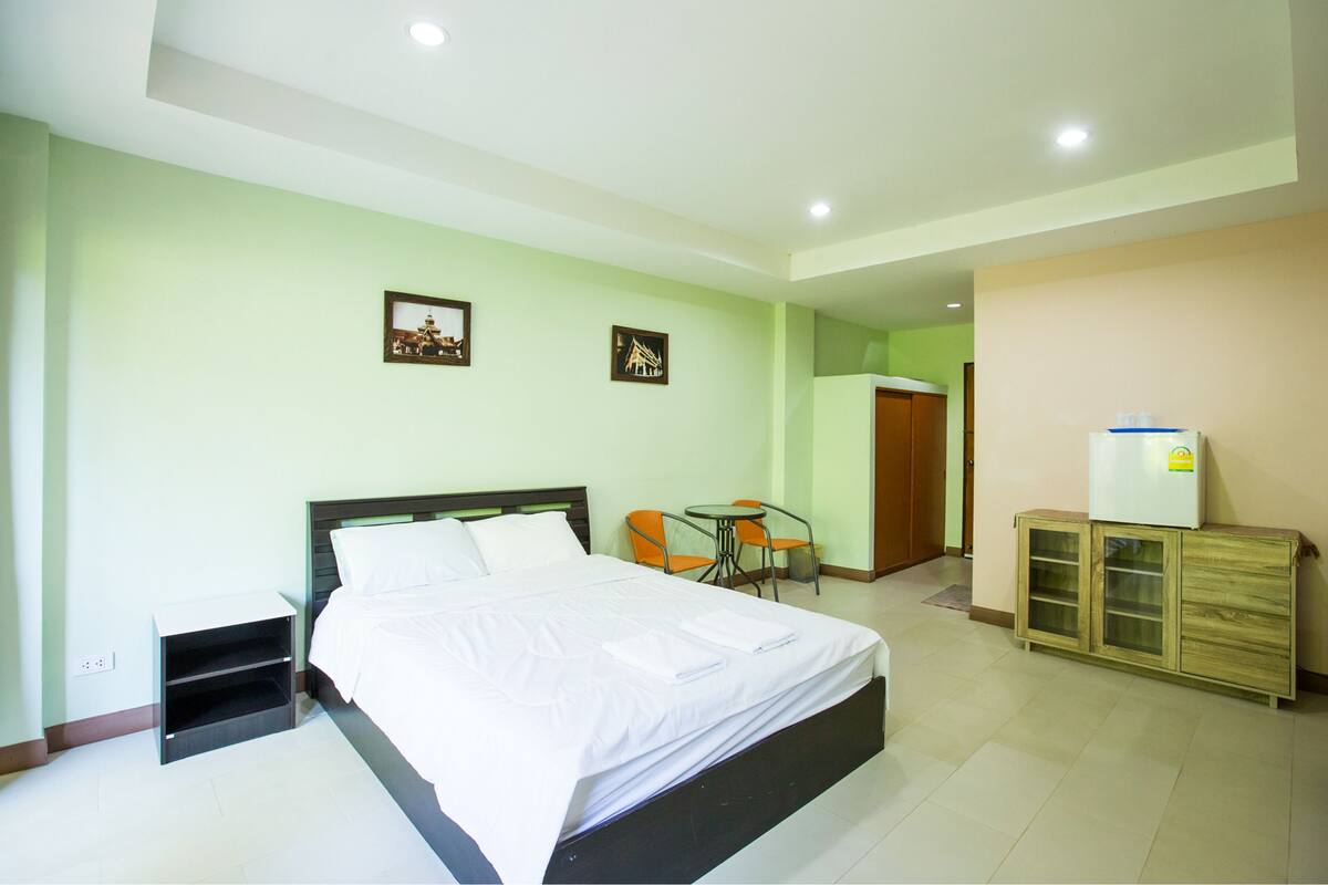 Una habitación de hotel con cama, una mesita con sillas, un armario y dos cuadros en la pared.