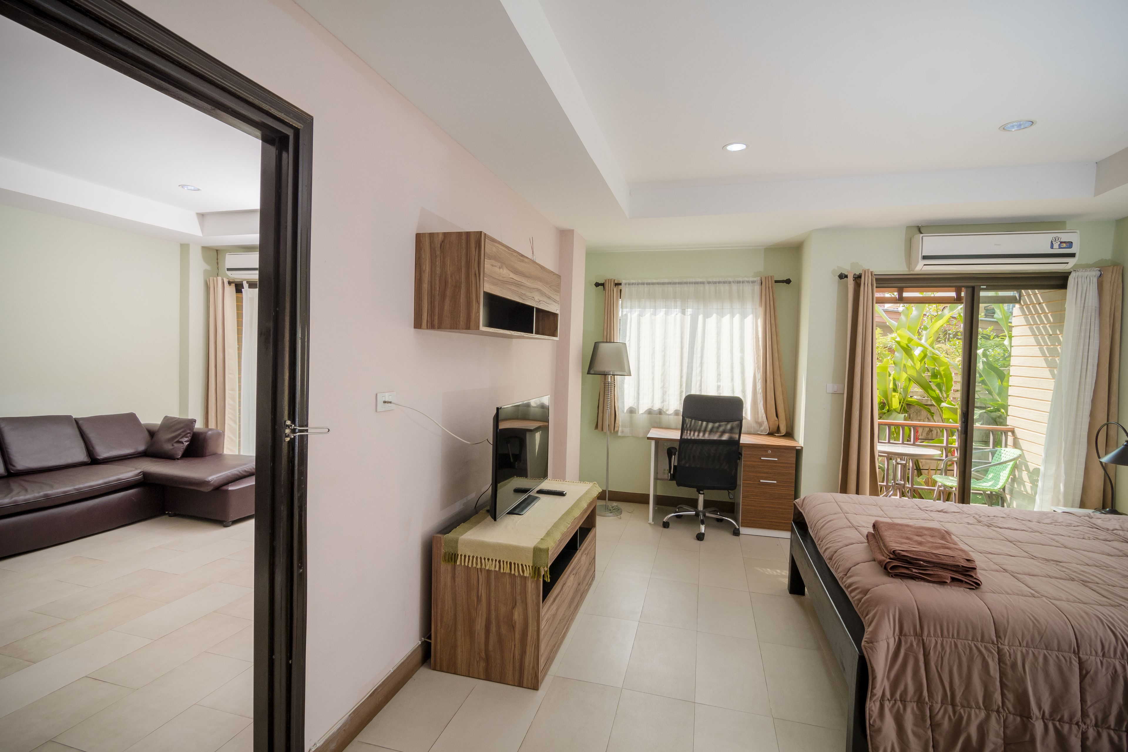 Una habitación de hotel moderna con sofá, escritorio, computadora, cama y vista al exterior.