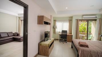 Una habitación de hotel moderna con sofá, escritorio, computadora, cama y vista al exterior.