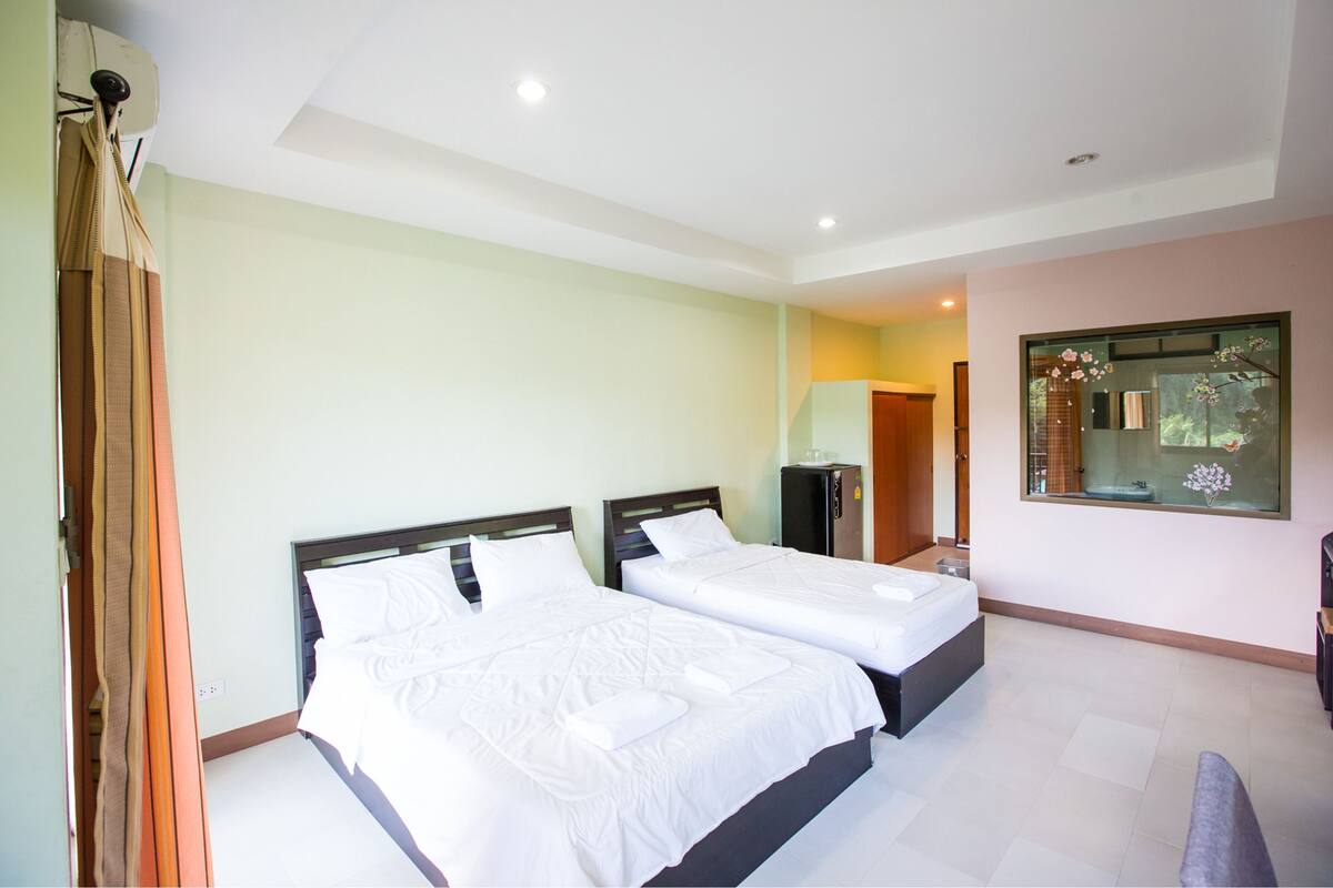 Habitación de hotel con dos camas, un baño y un ventanal con vistas.