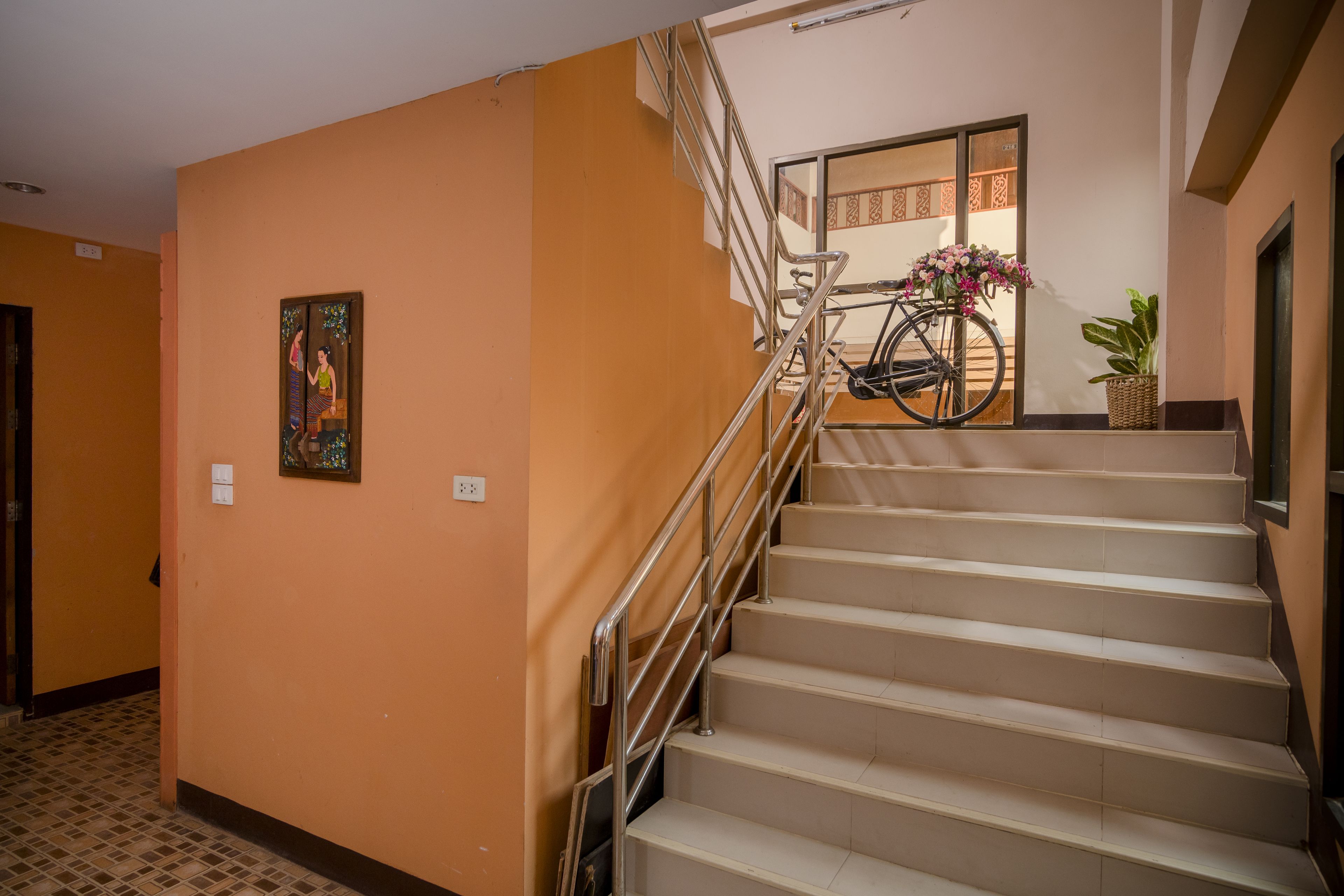 A staircase with metal railings, a bicycle, and a potted plant.