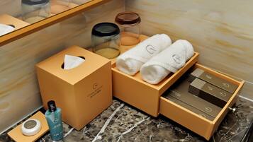 A neatly arranged bathroom with a marble floor, a towel rack, a tissue box, a soap dish, and a box of toiletries.