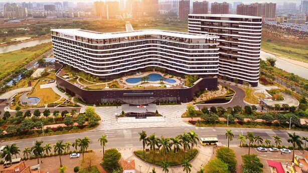 A modern hotel with a curved facade, multiple floors, and a central courtyard with water features. - Grand Skylight Int'l Hotel Huizhou (Huizhou)