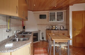 Cocina compacta con encimeras de granito, horno empotrado, microondas y un comedor con mesa y sillas.