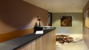 Un espace d’accueil avec un comptoir en bois, un vase de fleurs, une carte accroch ée au mur et un tapis en peau de vache sur le sol.