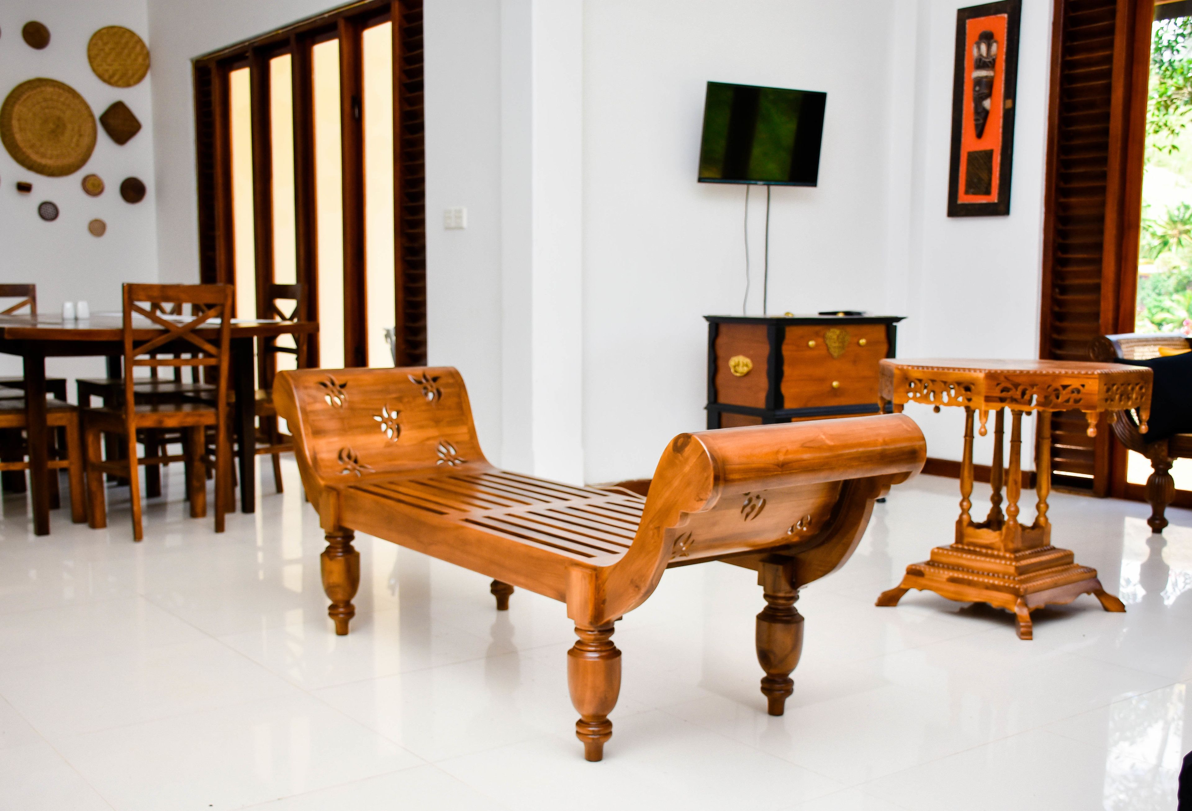 Quarto com um banco de madeira, uma mesa pequena e uma televisão na parede.