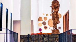Une statue sur un escalier, avec un mur en pierre et une rambarde en métal.