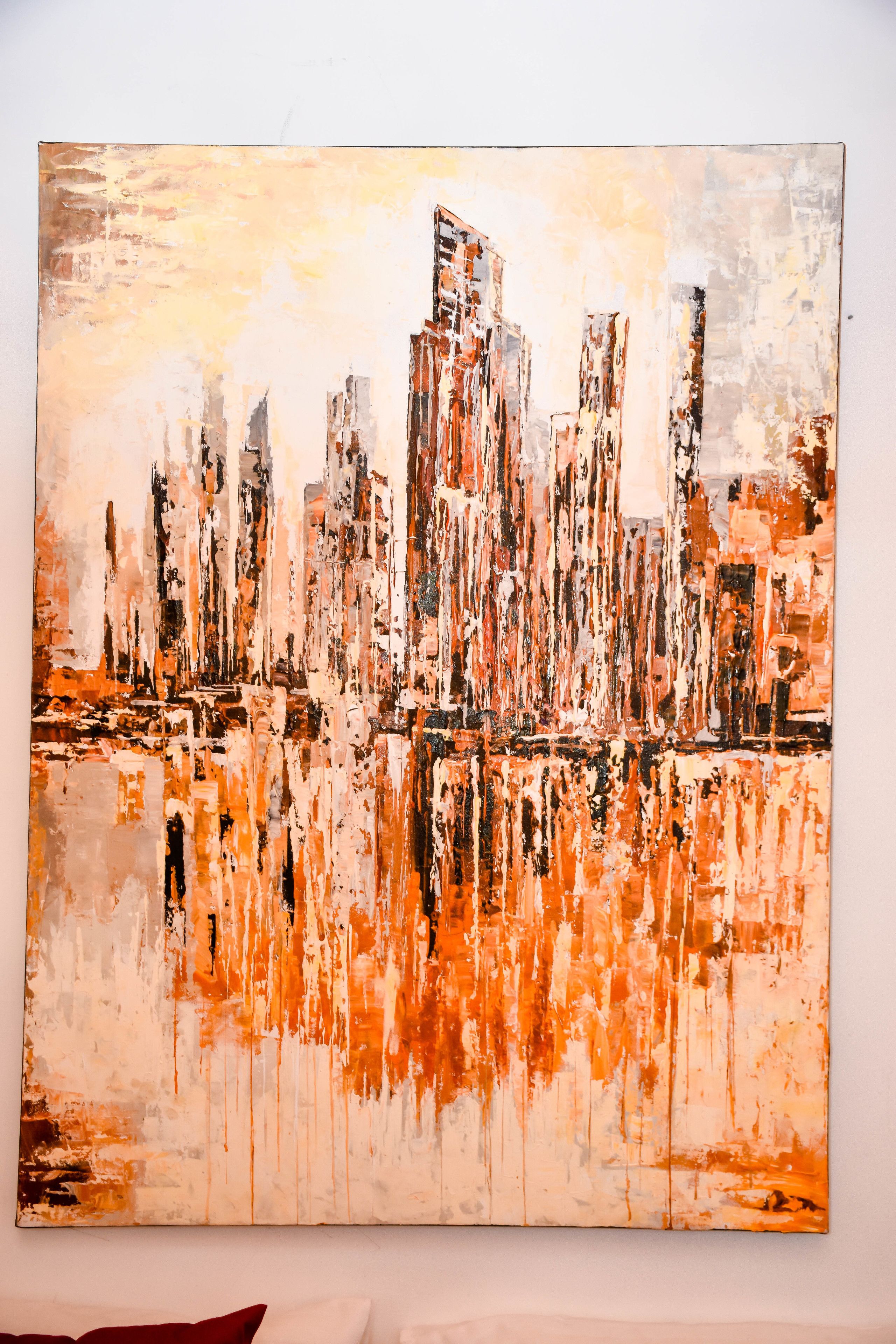Een groot abstract schilderij van een stadsgezicht met hoge gebouwen en een spiegelend wateroppervlak.