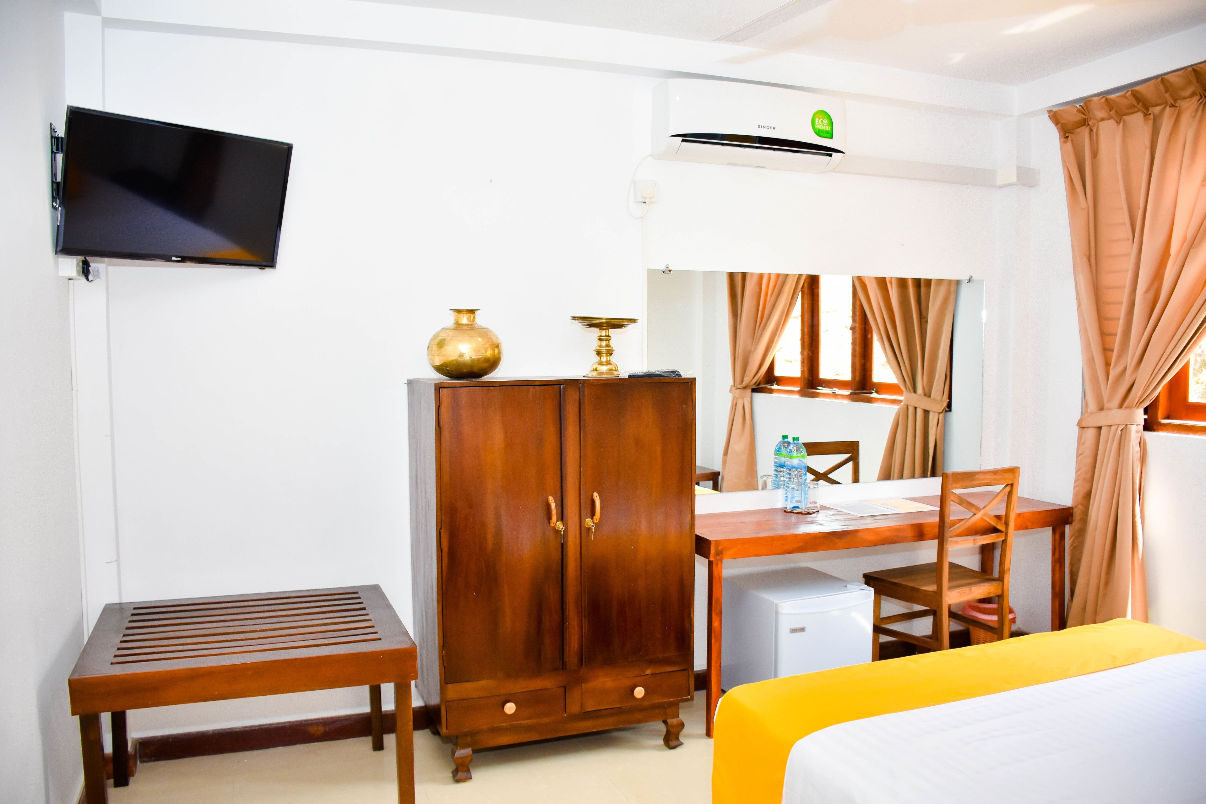 Une chambre d’hôtel équipée d’un lit, d’un bureau en bois, d’une télévision, d’une armoire et d’un appareil de climatisation.