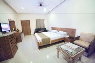 A hotel room with a bed, a desk with a computer, a chair, and a coffee table.