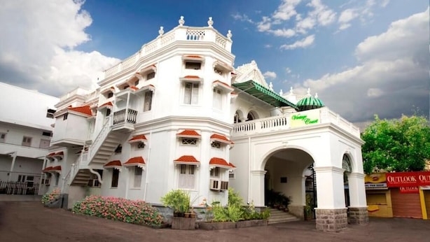 A multi-story building with a central archway, balconies, and a green awning. - Taj Mahal Hotel Abids (Hyderabad)