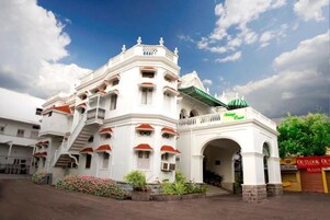 Un edificio de varios pisos con un arco central, balcones y un toldo verde.