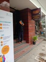 Una persona sale de un edificio, con un letrero de 'Dukadila Pizzeria' a la derecha.