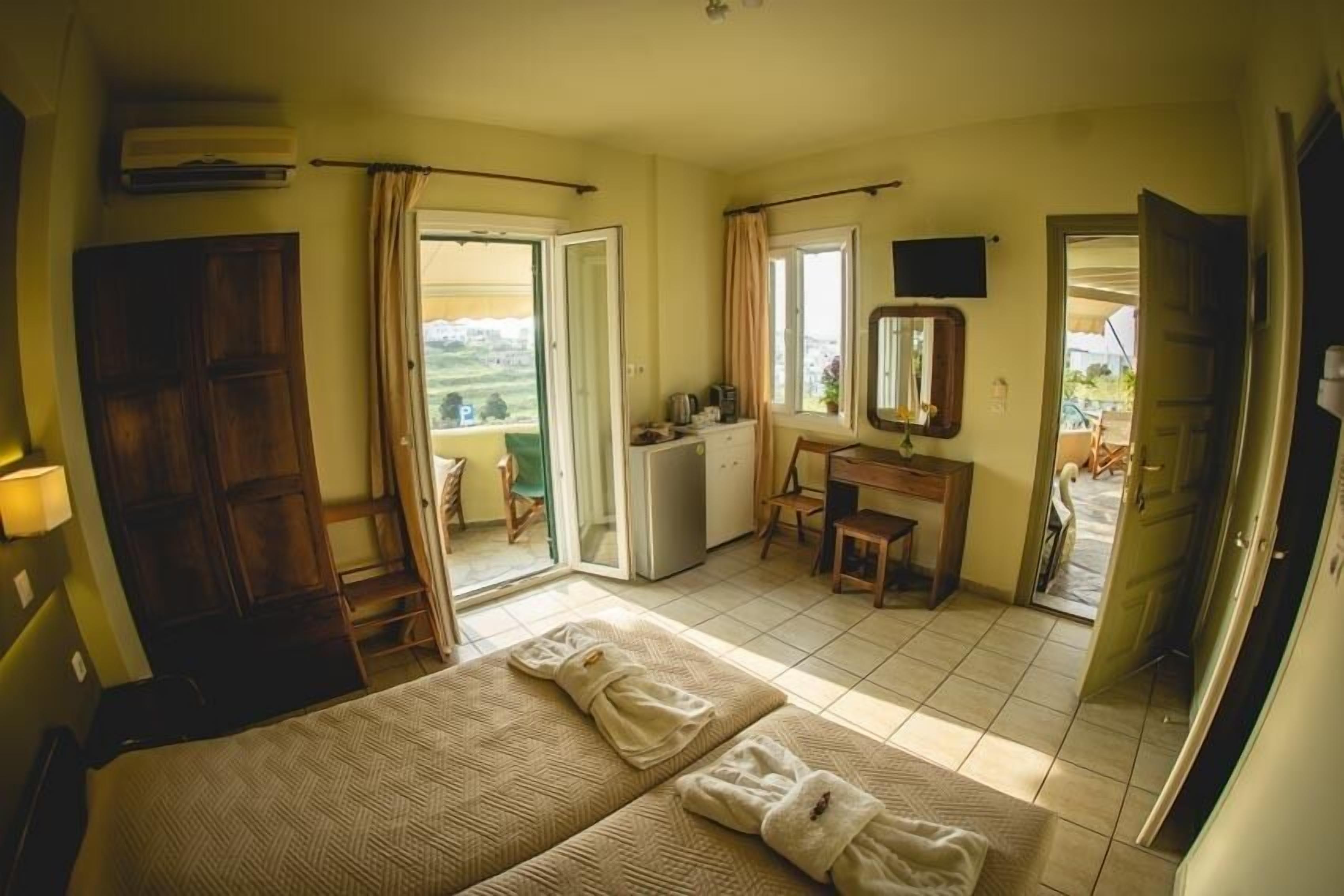 Une chambre avec un lit, un bureau, un miroir et une vue sur l’extérieur.