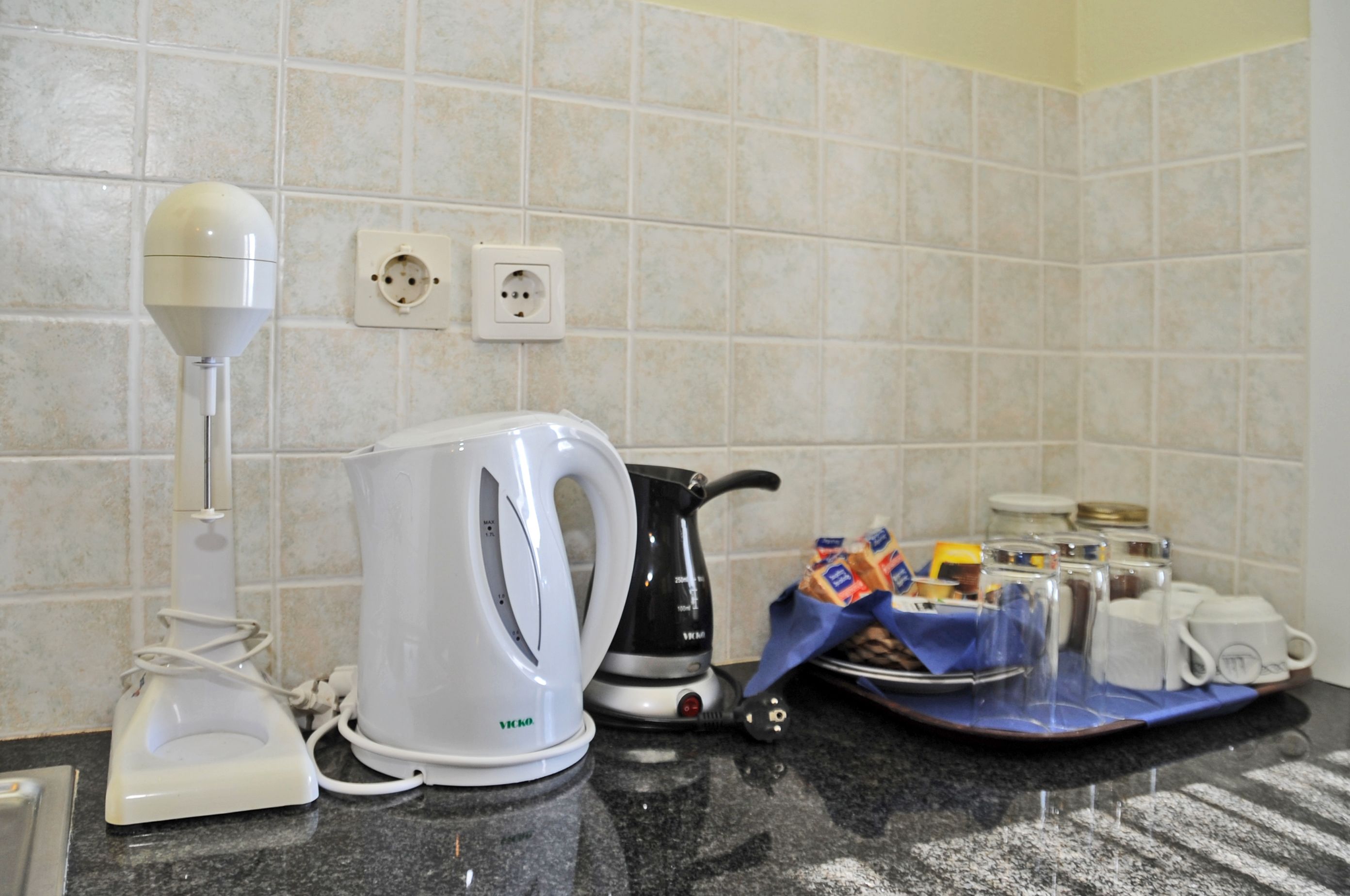 Una cocina con tetera, cafetera e interruptor de luz en la pared.