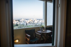 Ένα μπαλκόνι με θέα στην πόλη, ένα τραπέζι, δύο καρέκλες και ένα φυτό σε γλάστρα.