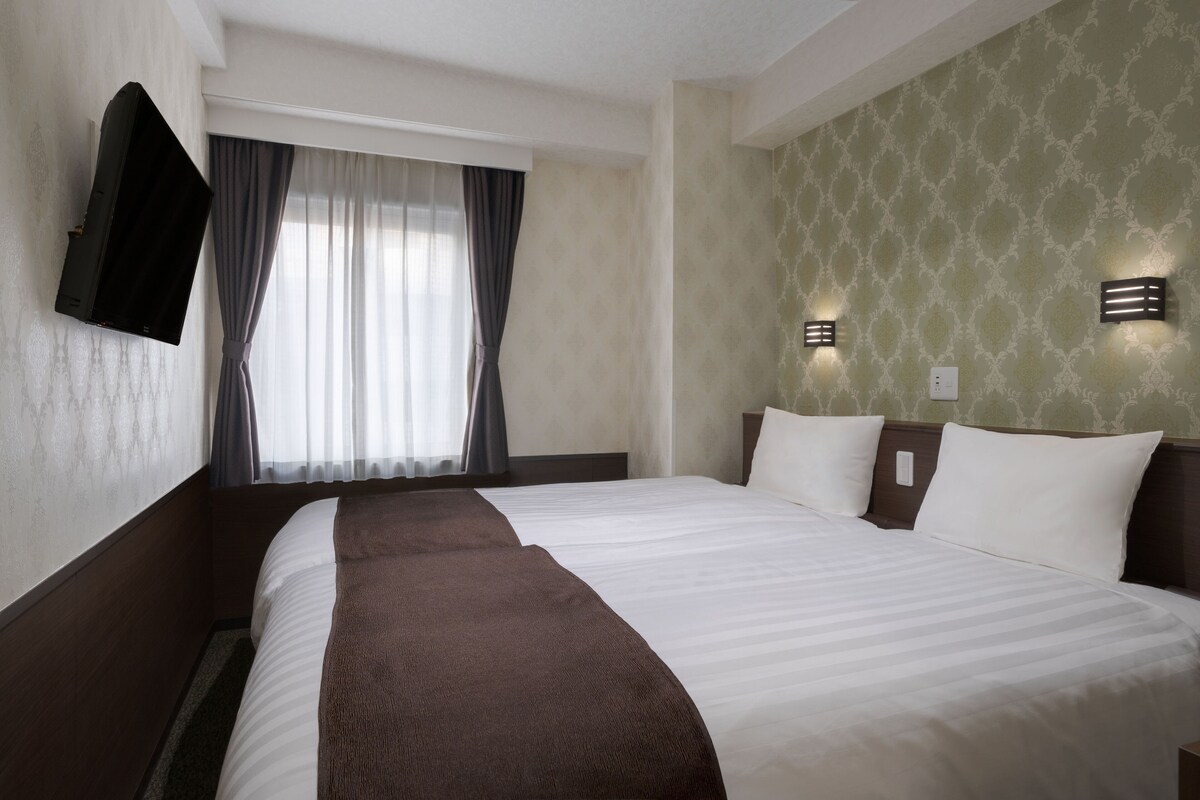 Habitación de hotel con una cama grande, un televisor de pantalla plana en la pared y dos lámparas de pared.