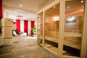 Une salle de spa moderne avec un sauna en bois, un fauteuil de massage et un mur rouge.
