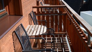 A wooden deck with metal chairs and a table, surrounded by a wooden railing. - Wellness Hotel Sauna (Mala Moravka)