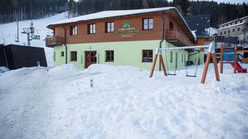 A hotel with a wooden facade and a balcony, surrounded by snow.