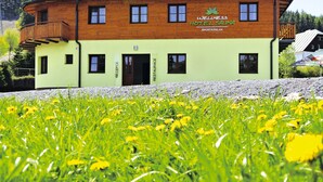 A two-story hotel with a wooden facade and a balcony. - Wellness Hotel Sauna (Mala Moravka)