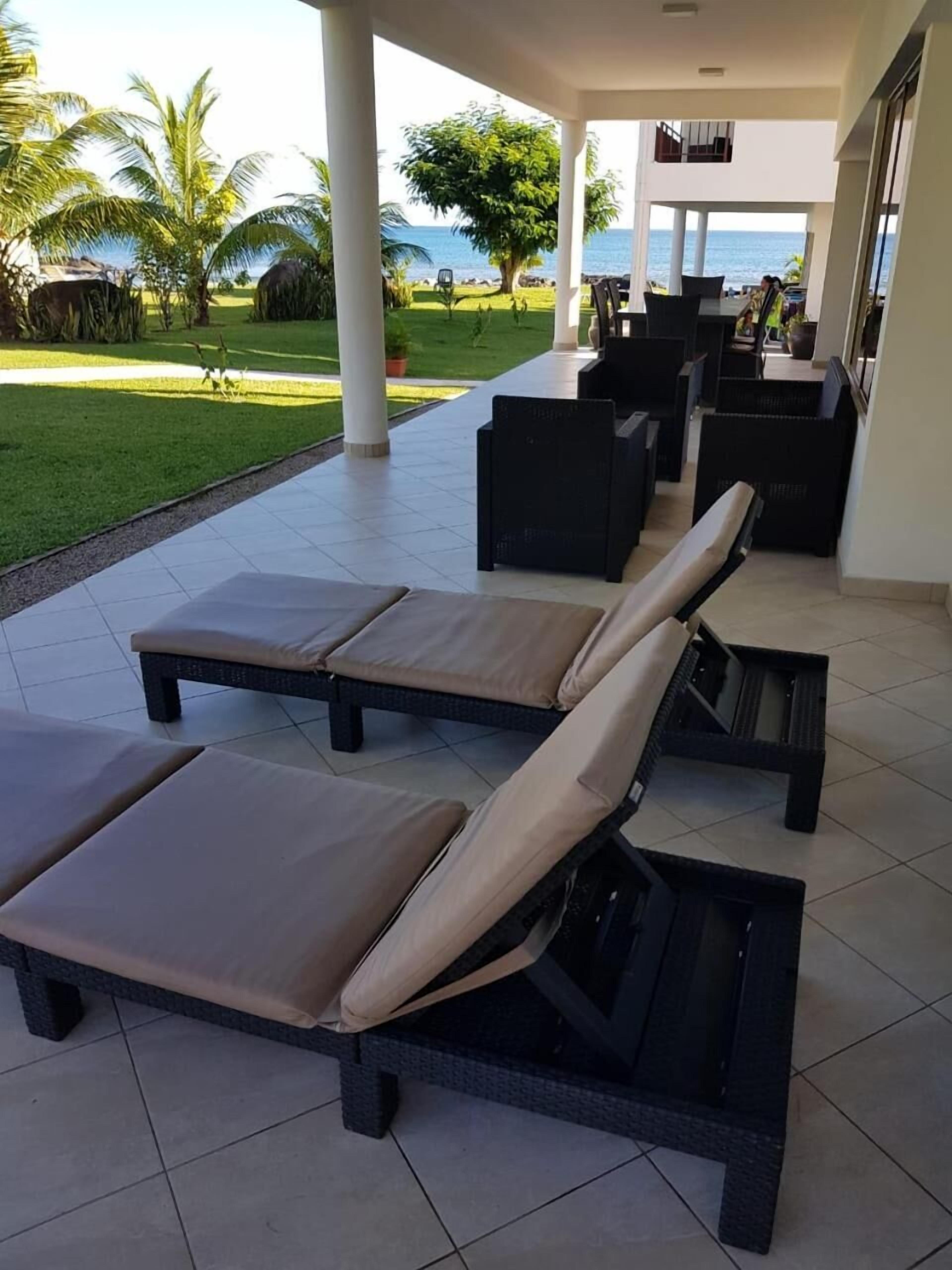 Un espace extérieur abrité, doté de fauteuils confortables et offrant une vue sur l’océan.