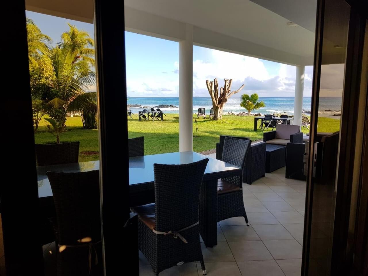 Une terrasse extérieure offrant une vue sur l’océan, aménagée avec des chaises et des tables en osier.