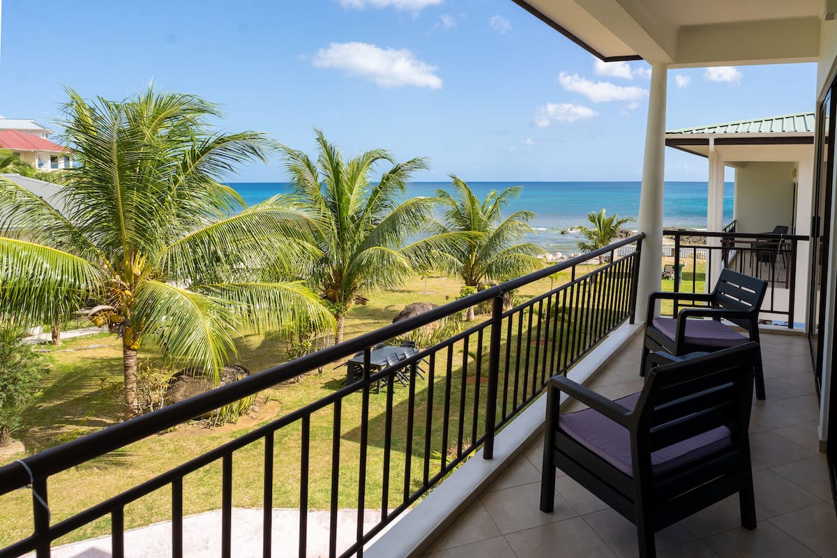 Ein Balkon mit Blick auf das Meer und Palmen.