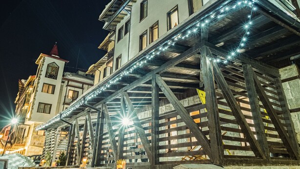Un edificio con estructura de madera y bancos afuera.
