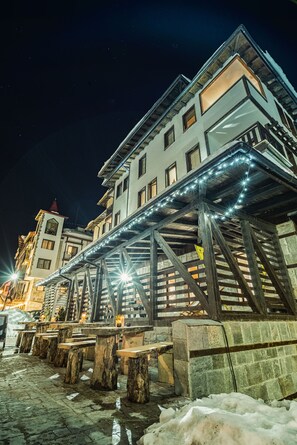 A building with a wooden structure and benches outside. - Green Life Family Apartments Pamporovo (Chepelare)