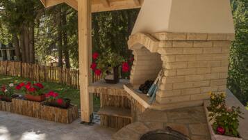 A stone fireplace with a chimney, surrounded by potted plants and a wooden deck.