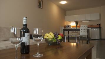 Ein Wohnzimmer mit Holztisch, einer Weinflasche, zwei Weingläsern und einer Obstschale.
