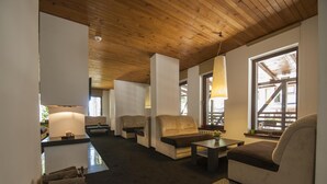 Amplia sala de estar con techo de madera, múltiples opciones de asientos y vistas a través de una ventana.