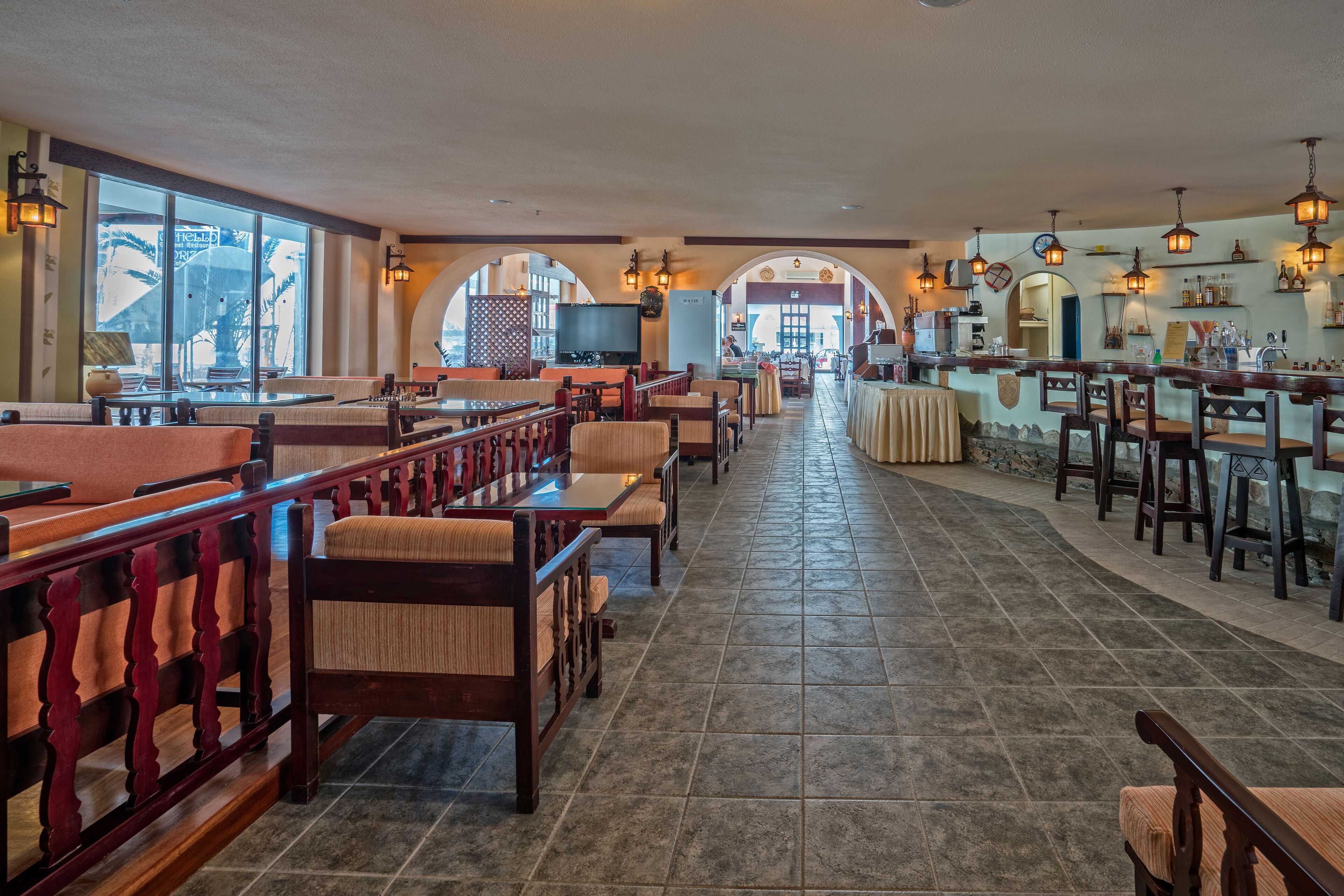 A restaurant with a long counter, booths, and a bar area.