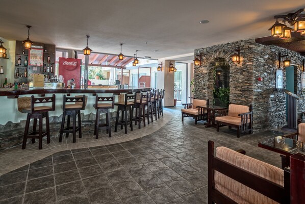A bar area with stools, a counter, and a stone wall.