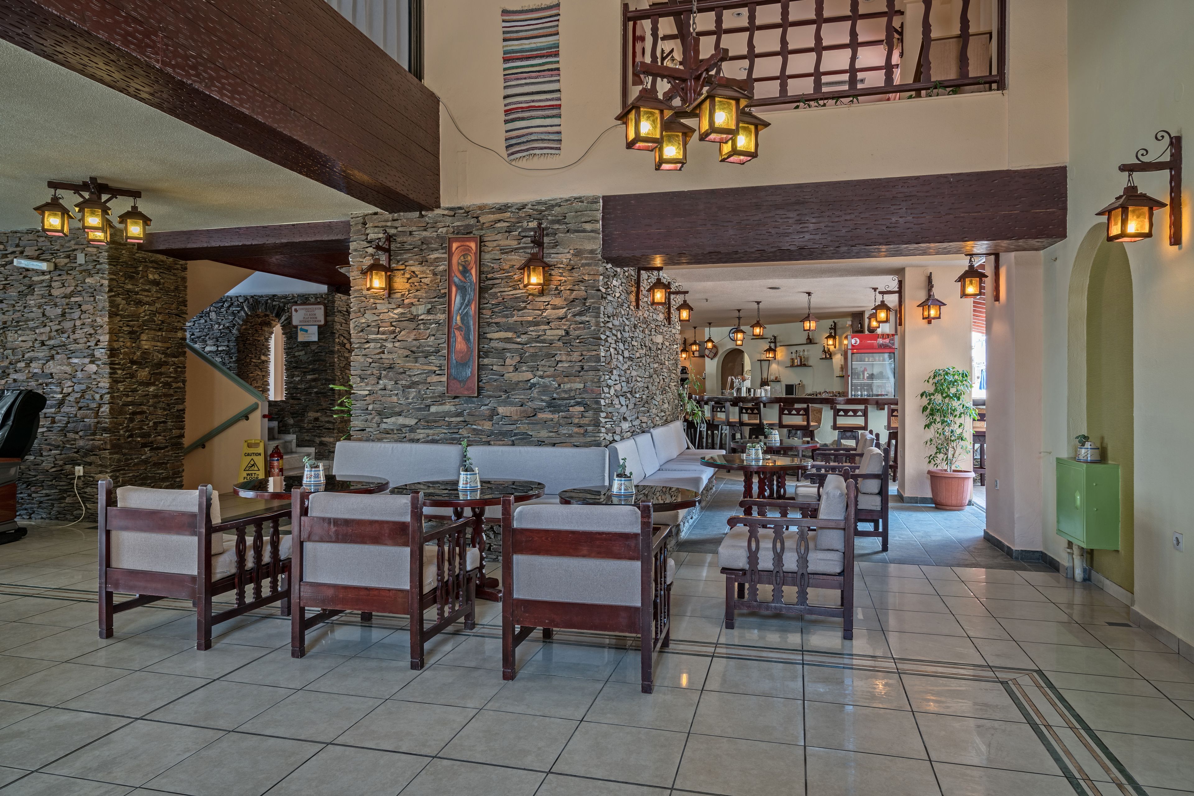 A spacious lobby with stone walls, wooden furniture, and hanging lanterns.