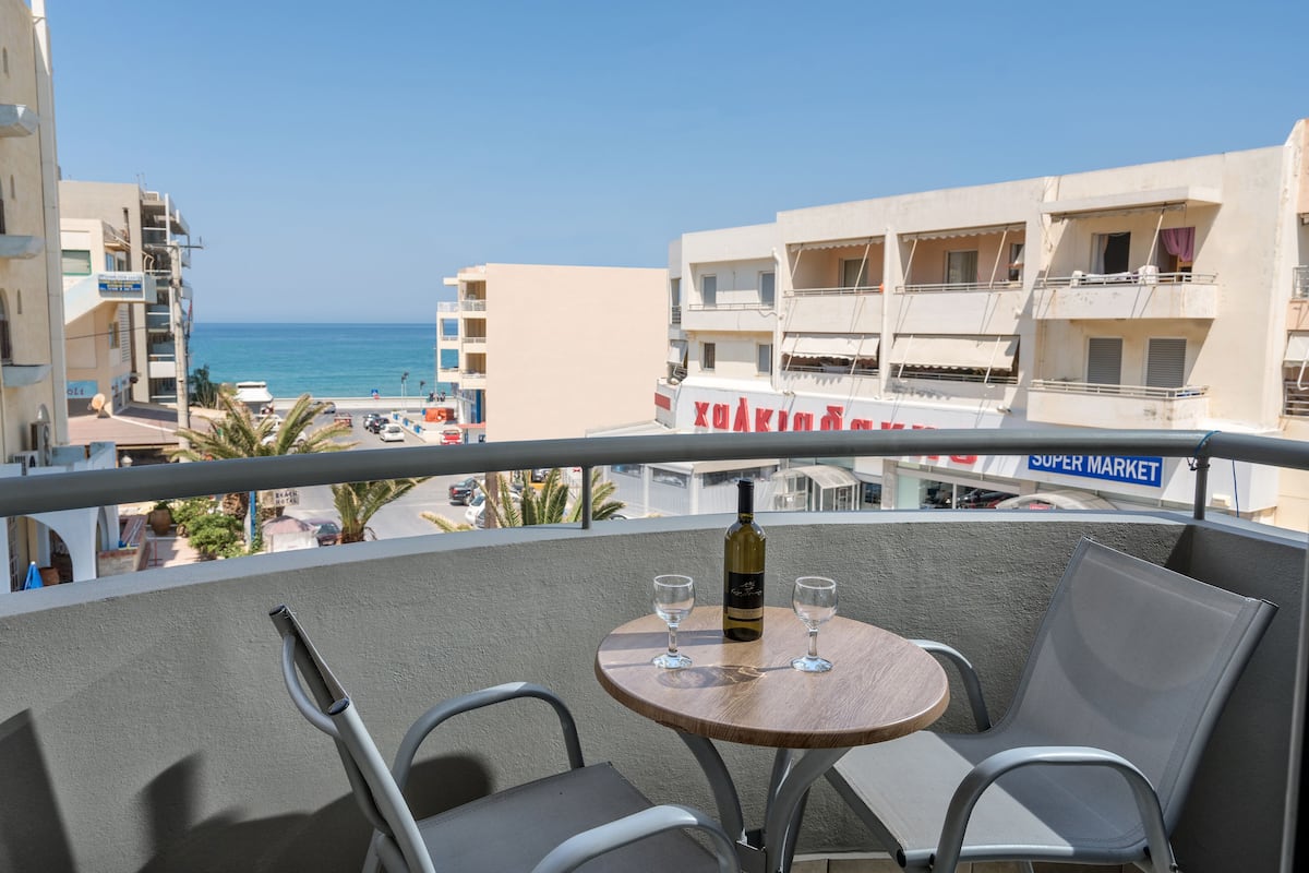 A balcony with a table, two chairs, a bottle, and two glasses.