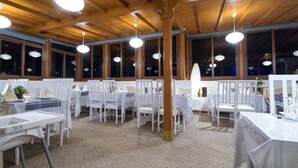 A restaurant with wooden ceiling beams, round pendant lights, and white tables and chairs. - Hotel Tarek (Chefchaouen)