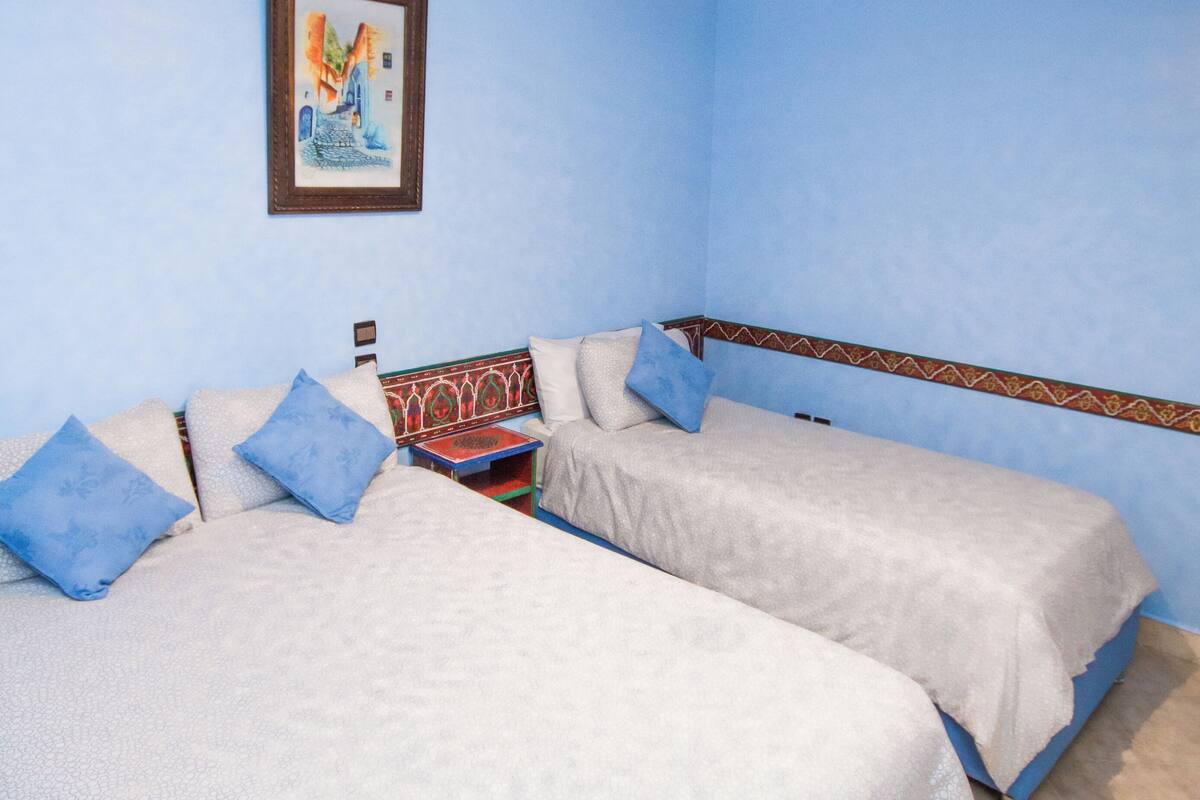 A room with two beds, a ceiling light fixture, and a framed picture on the wall.