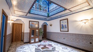 A room with a patterned floor, a decorative ceiling, and a view through a window. - Hotel Tarek (Chefchaouen)