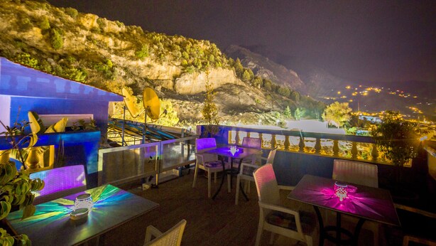 An outdoor dining area with tables and chairs, overlooking a mountainous landscape at night. - Hotel Tarek (Chefchaouen)