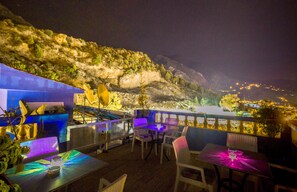 An outdoor dining area with tables and chairs, overlooking a mountainous landscape at night. - Hotel Tarek (Chefchaouen)