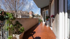 Balcó estret amb plantes en testos i vista cap a edificis al fons.